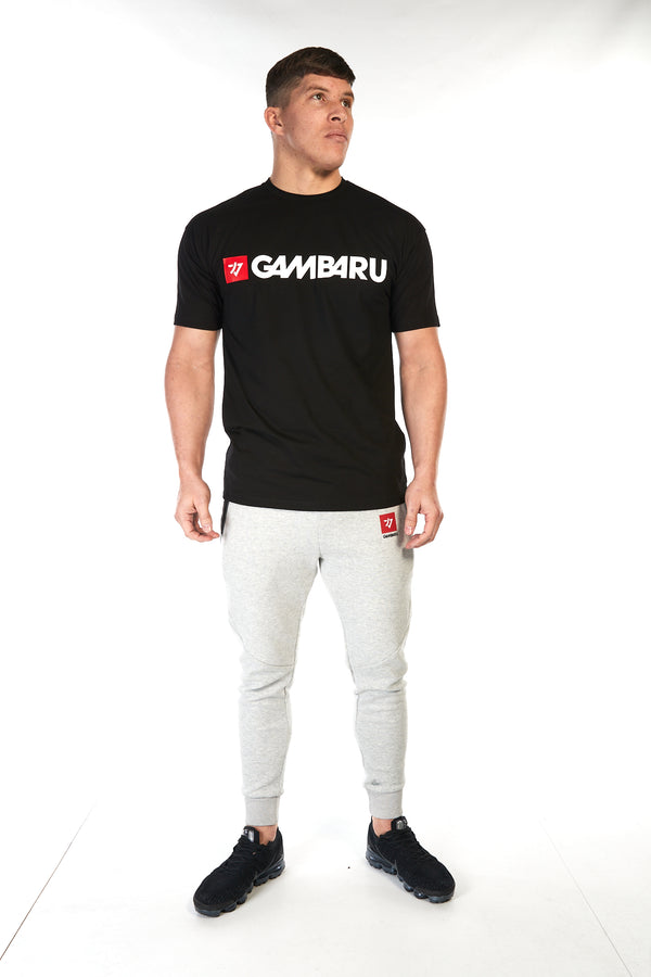 Man wearing unisex cotton t-shirt in black, with a bold white and red Gambaru Fightwear logo across the chest